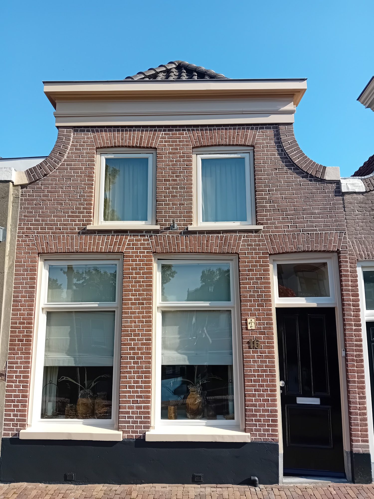 Oud bakstenen huis met witte kozijnen, donkere voordeur en zwarte plint