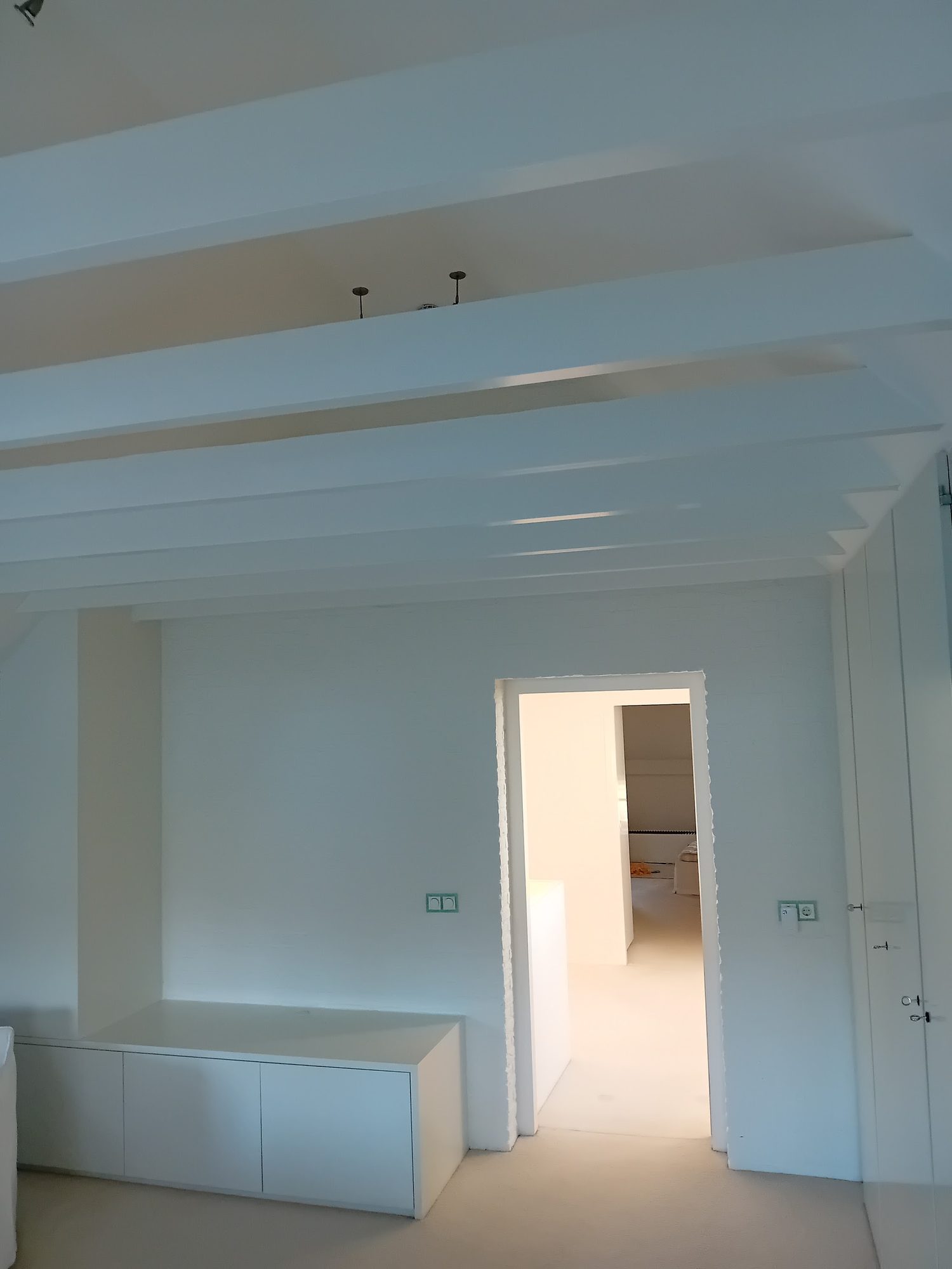 Wit plafond met balken, deuropening en witte inbouwkast